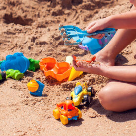 Imagem em close de criança brincando na areia da praia